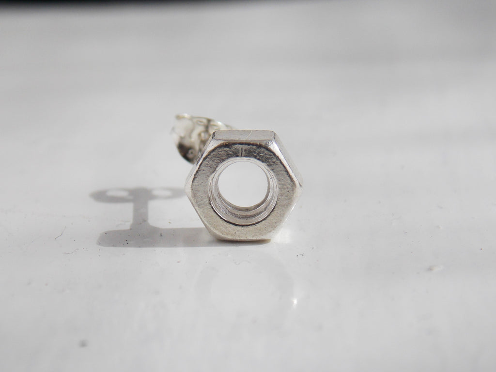 A solid silver nut earring sits on a white background